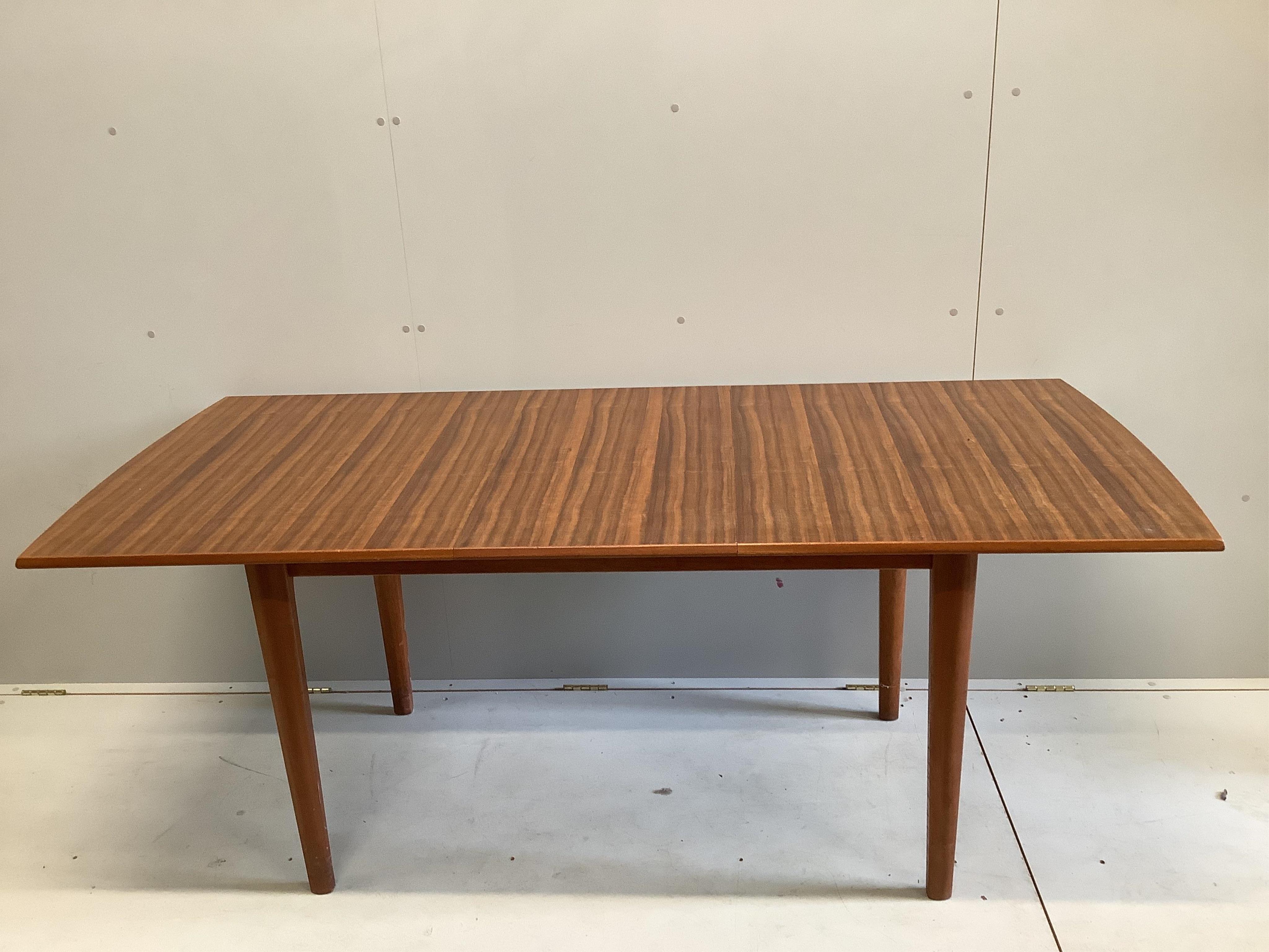 A mid century Gordon Russell teak dining suite comprising rectangular extending table, twelve chairs and a sideboard, width 140cm, depth 80cm, height 74cm. Condition - fair, with the leaf in it's an eight seater